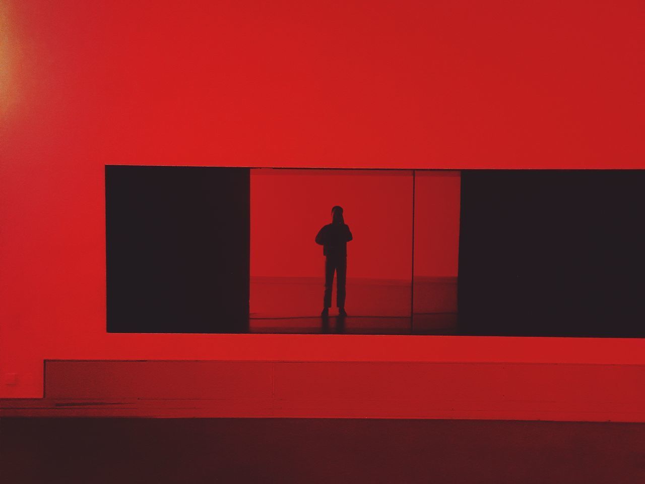 SILHOUETTE MAN STANDING AGAINST RED WALL