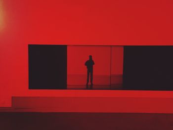 Rear view of silhouette man standing against red wall