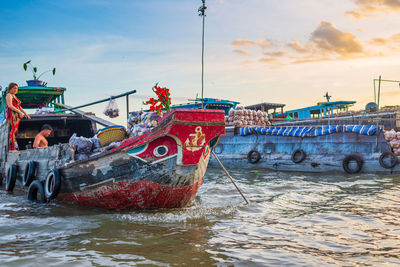 Fishing boats moored in sea against sky