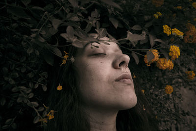 Close-up of woman with closed eyes against flowering plants