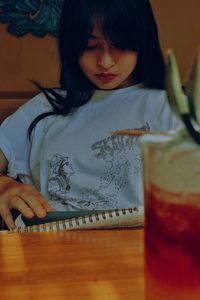 Portrait of young woman in glass on table