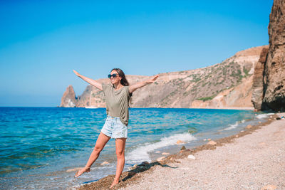 Full length of woman with arms outstretched standing against sea