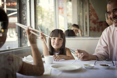 Happy granddaughters with grandfather sitting in restaurant