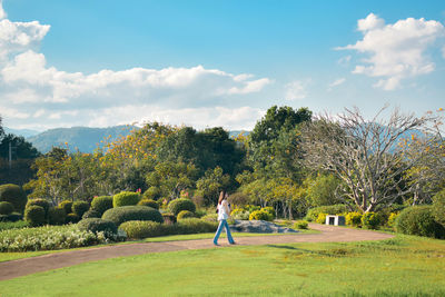 Rear view of woman walking on field against sky