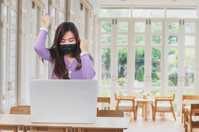 Woman using phone while sitting on table