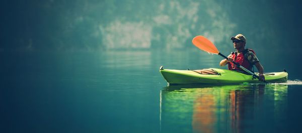 Man sitting in boat floating on lake