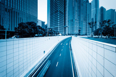 Road amidst buildings in city against sky