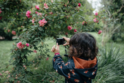 Rear view of woman photographing at camera