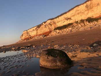 Rock formation on shore against sky