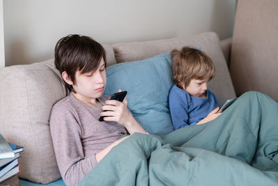 Rear view of friends relaxing on sofa at home