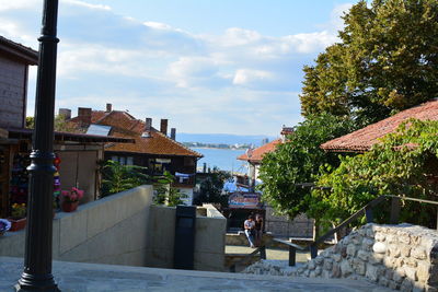 Buildings in town by sea against sky