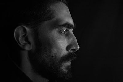 Close-up portrait of young man against black background