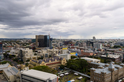 High angle view of city buildings against cloudy sky