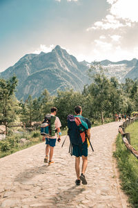 Rear view of people walking on mountain against sky