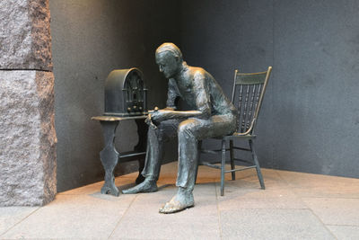 Man sitting on chair against wall