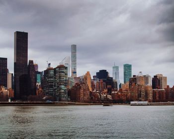 Sea by buildings against sky in city