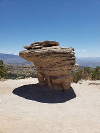 Shadow of rock on land against clear blue sky