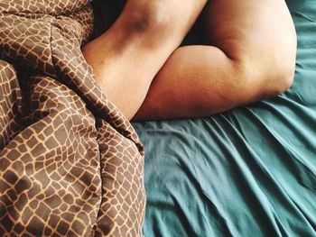 Low section of woman lying on bed