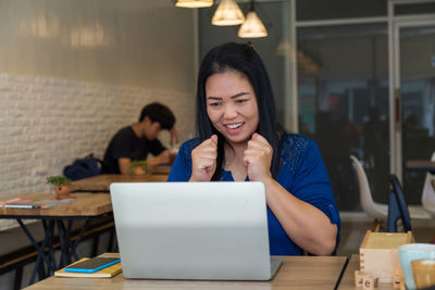 Young woman using phone while sitting on table