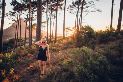 Full length of woman photographing against sky during sunset