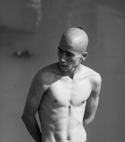 Portrait of shirtless man standing against wall