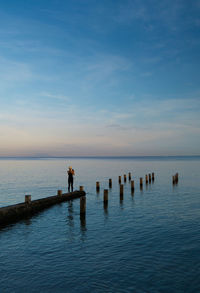 Rear view of people on pier over sea against sky