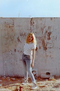 Portrait of young woman standing against wall