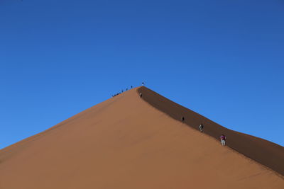 Low angle view of a desert against clear blue sky