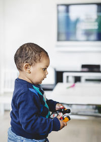 Side view of boy playing with operating remote control of model airplane at home