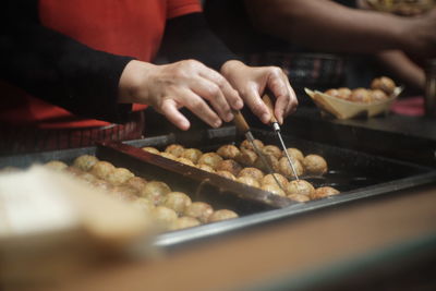 Cropped hands of person frying food in cooking oil