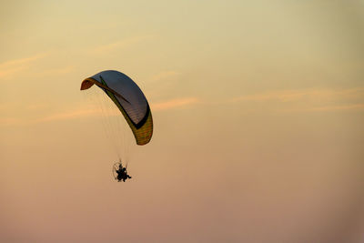 Person paragliding against sky during sunset