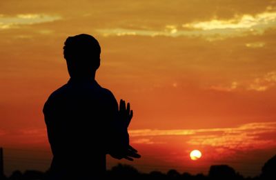 Silhouette man standing against sky during sunset