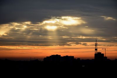 Silhouette of buildings against cloudy sky during sunset