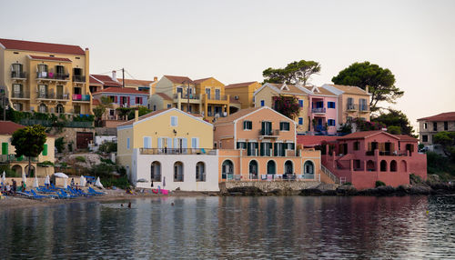 Residential buildings by river against sky