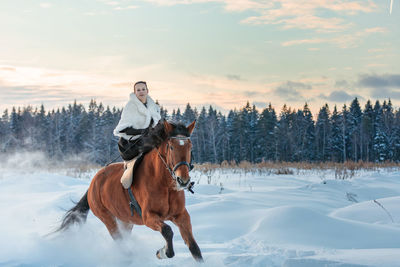 Man riding horse on snow covered field