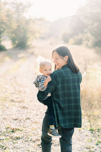 Side view of mother and daughter walking on field