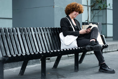 A non-binary person is using the smartphone to review social media or some apps