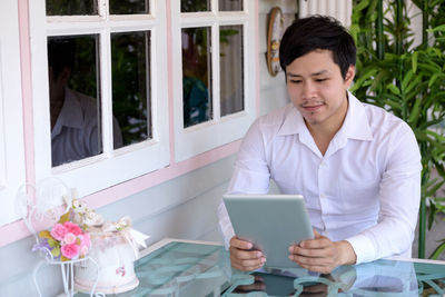 Young man using mobile phone while sitting on table