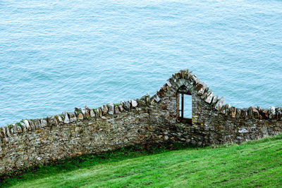 High angle view of stone wall by sea