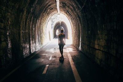 Rear view of woman standing in tunnel