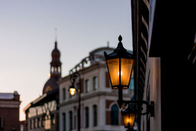 Low angle view of illuminated street light against buildings and sky