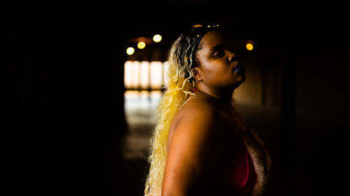 Side view of woman looking away against black background