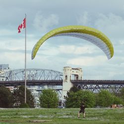 Man landing with parachute against burrard bridge at vanier park