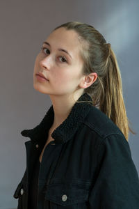 Portrait of young woman against gray background