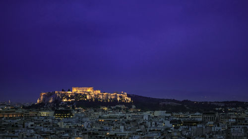 Illuminated buildings in city against clear sky at night