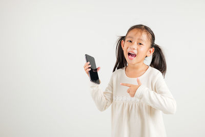 Portrait of young woman using mobile phone against white background