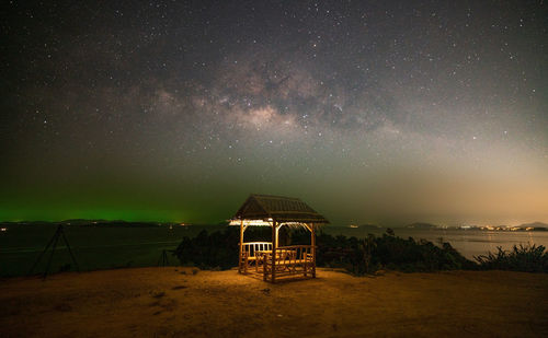 Lifeguard hut by building against sky at night