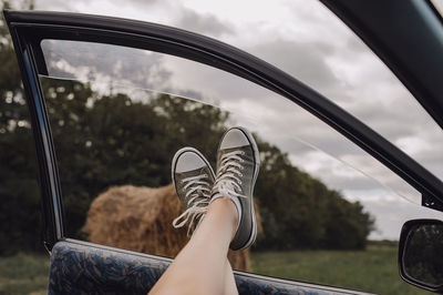 Low section of woman against car window