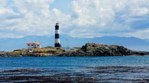 Lighthouse by sea against sky