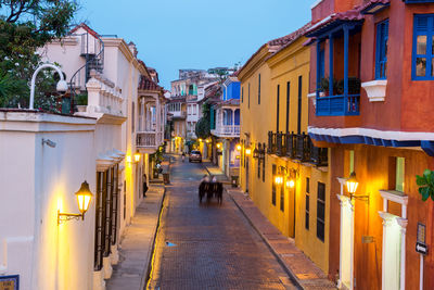 Cart moving on street amidst buildings during sunset